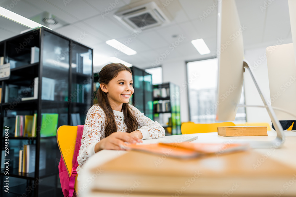 adorable smiling schoolgirl using desktop computer in library adorable smiling schoolgirl using desktop computer in library
