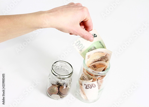 hand putting some money into a glass jar