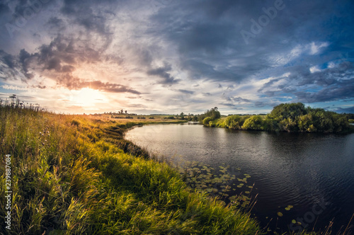 landscape of the riverbank at sunset with the sun above the horizon