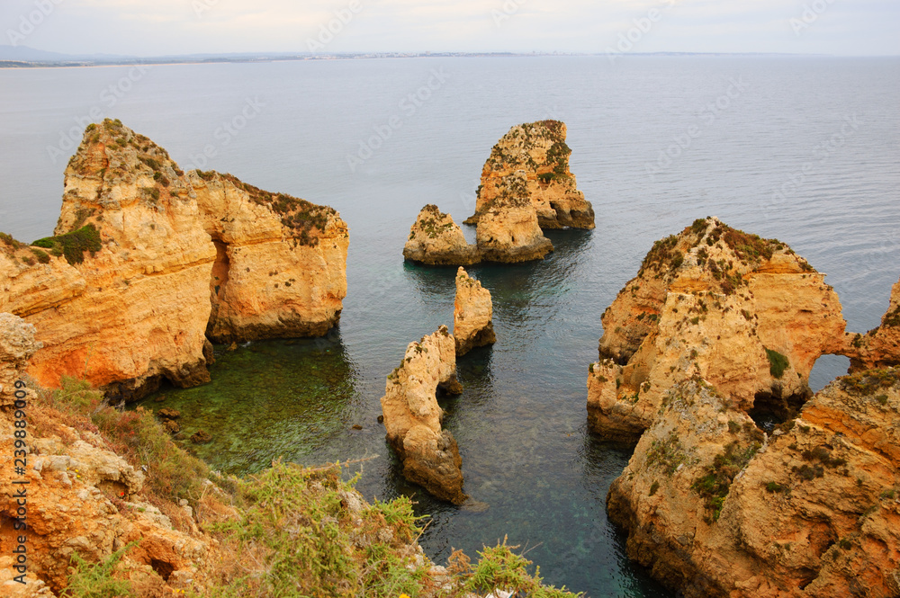 Unique stone arches, caves, rock formations at Dona Ana Beach (Lagos, Algarve coast, Portugal) in the evening light. 