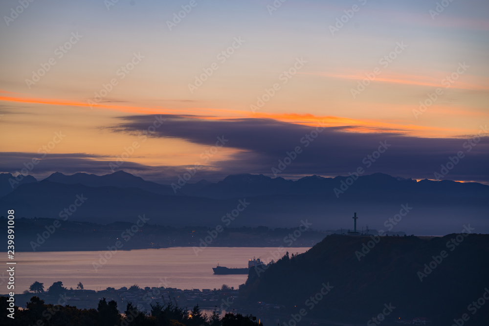 bay of the city of Puerto Montt from the heights at sunrise on a day partially covered with clouds