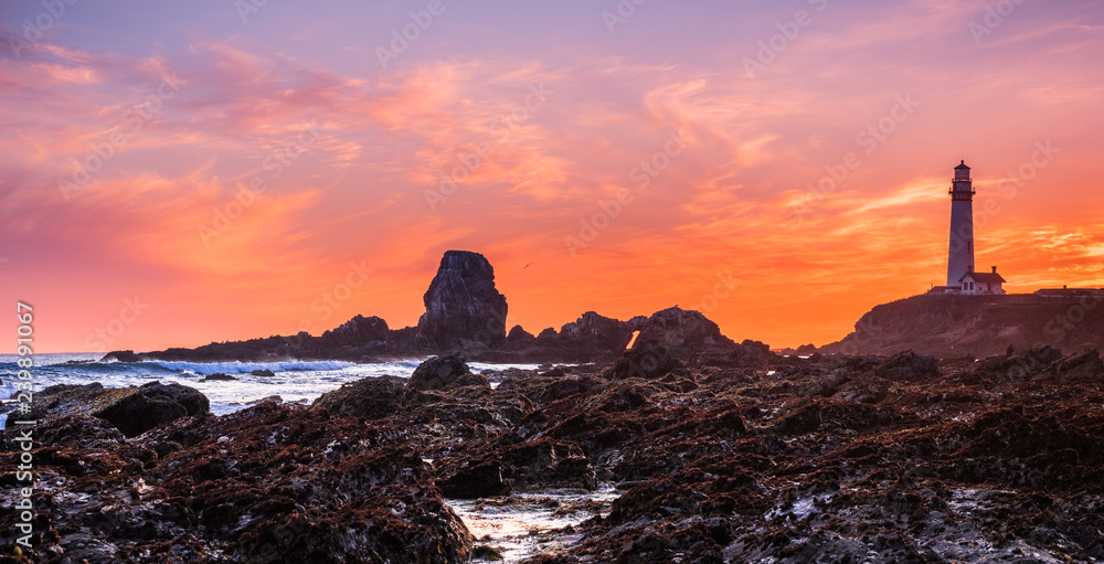 Rocky shoreline close to the Pigeon Point Lighthouse on the Pacific Ocean coastline, sunset landscape; Pescadero, California