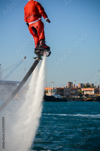 Vertical View of Santa Claus Flying on Flyboard on Blur Background photo