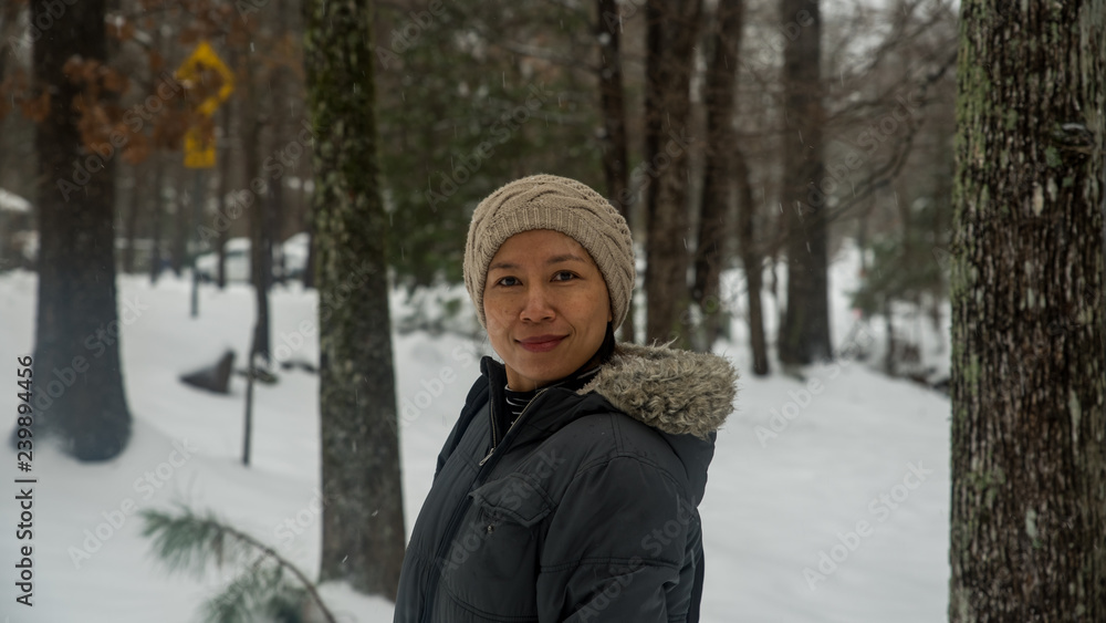Asian woman with biege knit hat standing in snow Asian woman with biege knit hat standing in snow