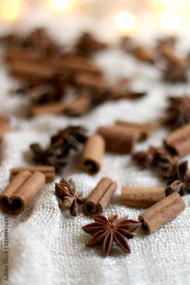 Cinnamon sticks and anise on beige tablelcloth. Fairy lights in the background. Selective focus. Cinnamon sticks and anise on beige tablelcloth. Fairy lights in the background. Selective focus.