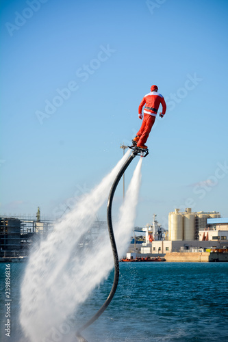 Vertical View of Santa Claus on Flyboard on Blur Background photo