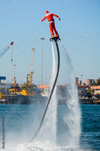 Vertical View of Santa Claus on Flyboard on Blur Background photo