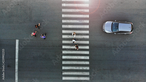 Aerial. Pedestrian crossing crosswalk, crowd of people and stopped car.