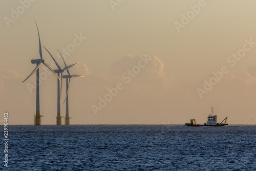 Valokuva Offshore wind farm turbines on the horizon with passing ship