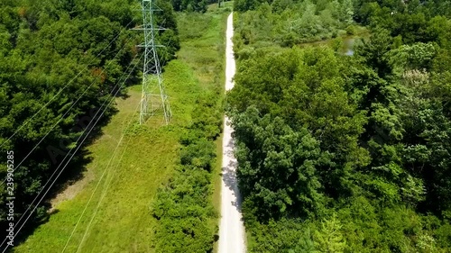 Drone footage of a rural trail and trees, and some small ponds as well. Big power lines also. Pretty.  Sunny. photo