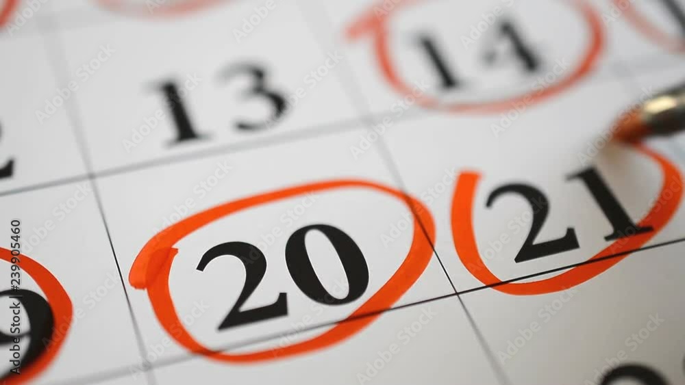 Signing a day on a calendar by red pen twentieth mark Signing a day on a calendar by red pen twentieth mark