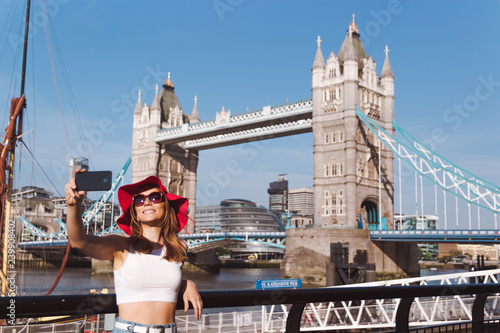 Young woman with red hat taking selfie in London with Tower Bridge on background photo