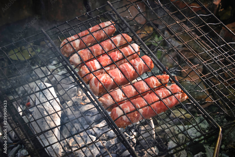 Grilling sausages wrapped becon on  grill