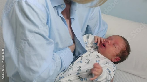 Mother breast feeding and hugging her baby.Young mother feeding breast her babyboy at home in blue-white room. Mom breastfeeding her child whith breast milk