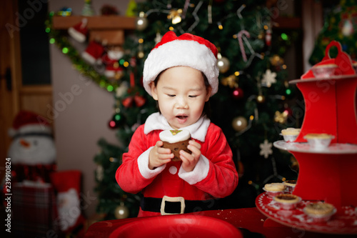 toddler baby girl eating Christmas cake in front of christmas tree
