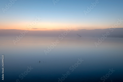 fog on a lake at sunrise with a pole in the background