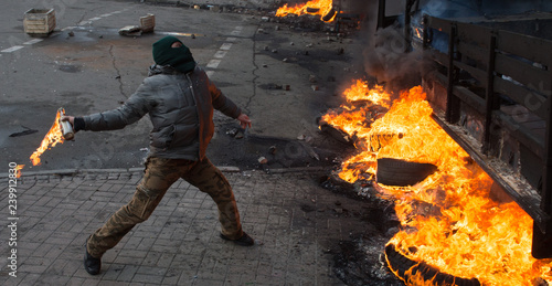 Foto Street Protestant with a Molotov cocktail against a fire