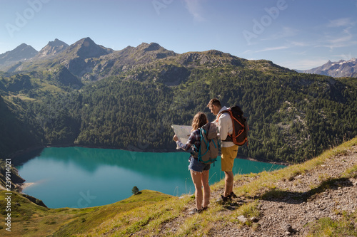 Young couple with backpack reading a map in the swiss alps. Lake ritom as background photo