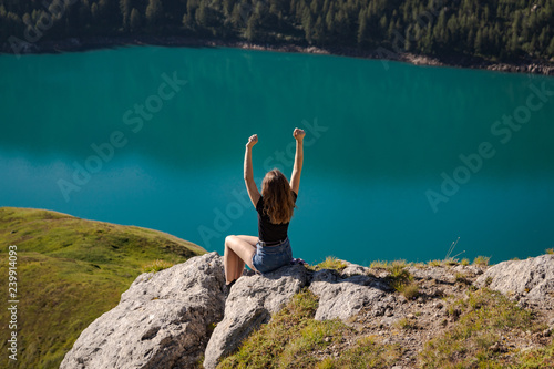 positive young woman enjoying freedom on the top of the mountain with the lake ritom as background photo