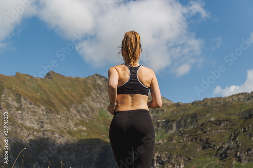 Young woman running in the mountains during a sunny day