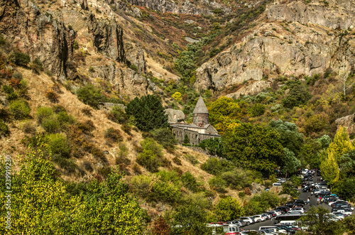Geghama ridge gorge with Geghard monastery and the road leading pilgrims to the temple on the background of autumn trees in Armenia