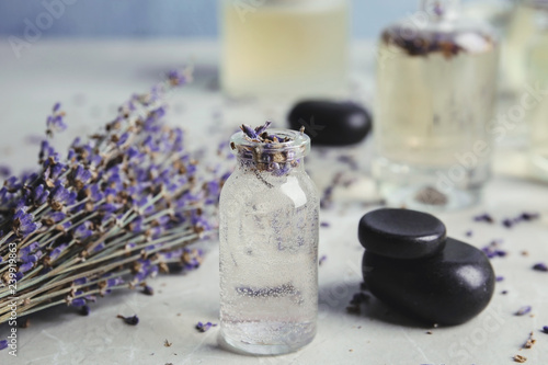 Fototapeta Naklejka Na Ścianę i Meble -  Bottles with natural herbal oil and lavender flowers on color table, closeup