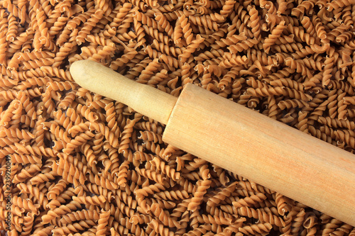 Top view Wholemeal Pasta texture. dough roller on Integral fusilli on wooden table