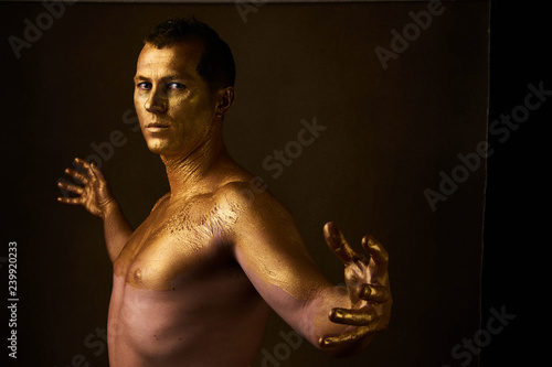 Body art paint with gold on face of man over dark background 