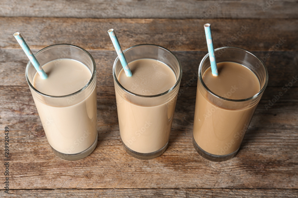 Glasses with protein shakes and straws on wooden background Glasses with protein shakes and straws on wooden background