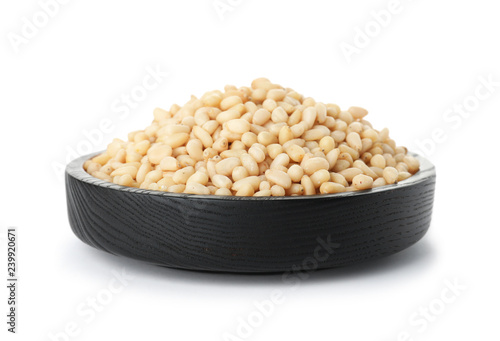 Plate with pine nuts on white background