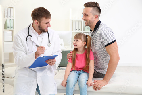 Father and daughter visiting pediatrician. Doctor working with patient in hospital