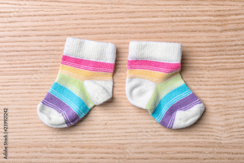 Pair of cute child socks on wooden background, top view
