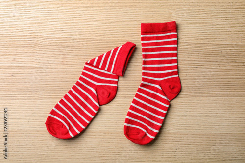 Pair of cute child socks on wooden background, top view
