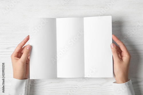 Woman holding blank brochure mock up on light background, top view photo