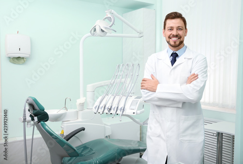 Professional male dentist in white coat at workplace. Space for text