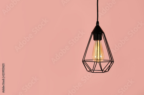 Modern hanging lamp on color background, space for text. Idea for interior design