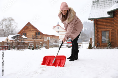 Young woman cleaning snow with shovel near her house