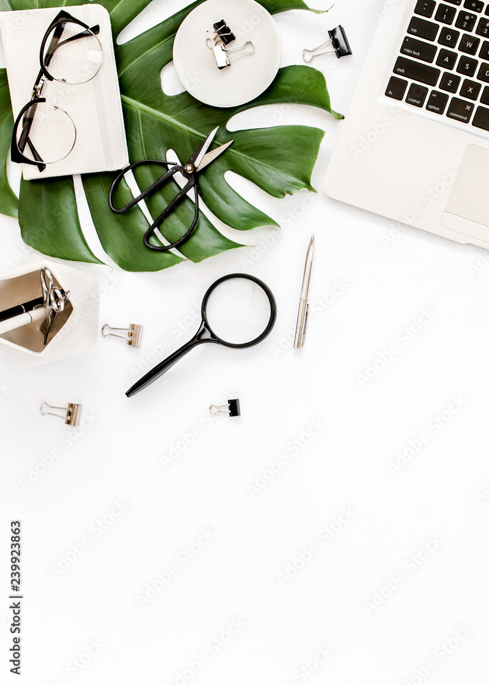 Home office workspace mockup with laptop, tropical leaves Monstera, clipboard, notebook and accessories on white background. Flat lay, top view