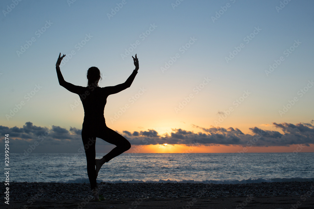 silhouette of person doing yoga on the beach at sunrise