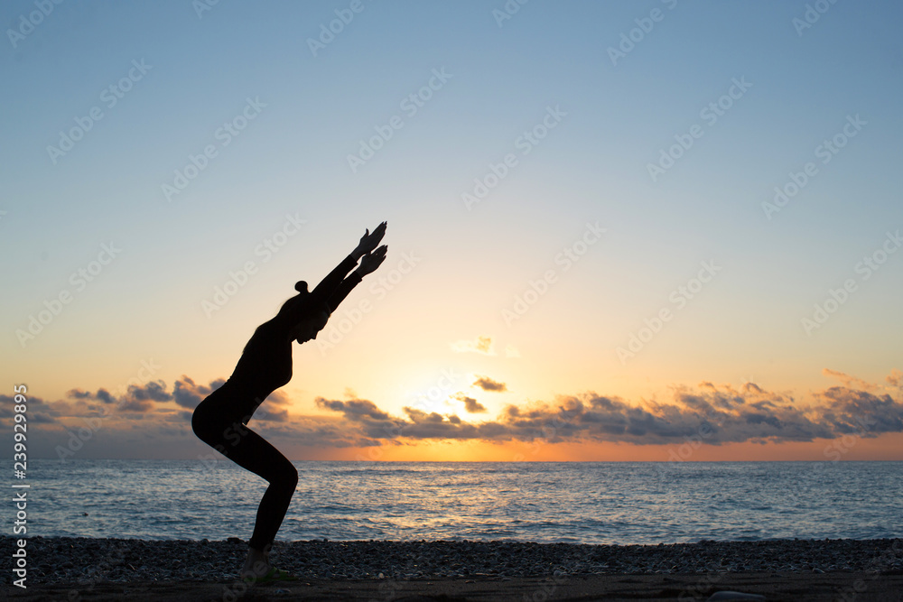 silhouette of person doing yoga on the beach at sunrise