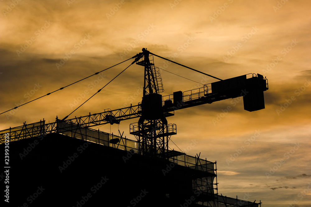 silhouette of construction cranes at sunset
