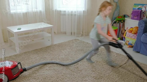 a little girl with blond hair cleans up with a vacuum cleaner, brings order and cleanliness, helps mom