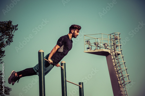 Young man exercising on gymnastic bar in park at morning © Dalibor Danilovic