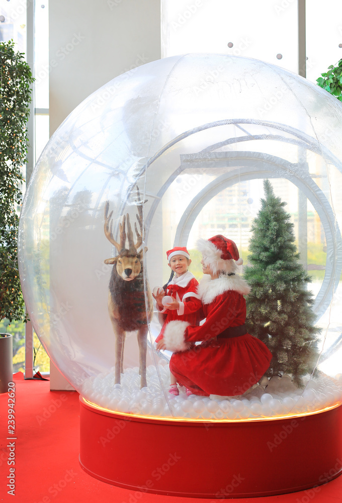 Happy little child girl and mother in santa costume dress has fun in big  winter Snow globe with reindeer on christmas time. Merry Xmas and happy new  year. Stock Photo | Adobe