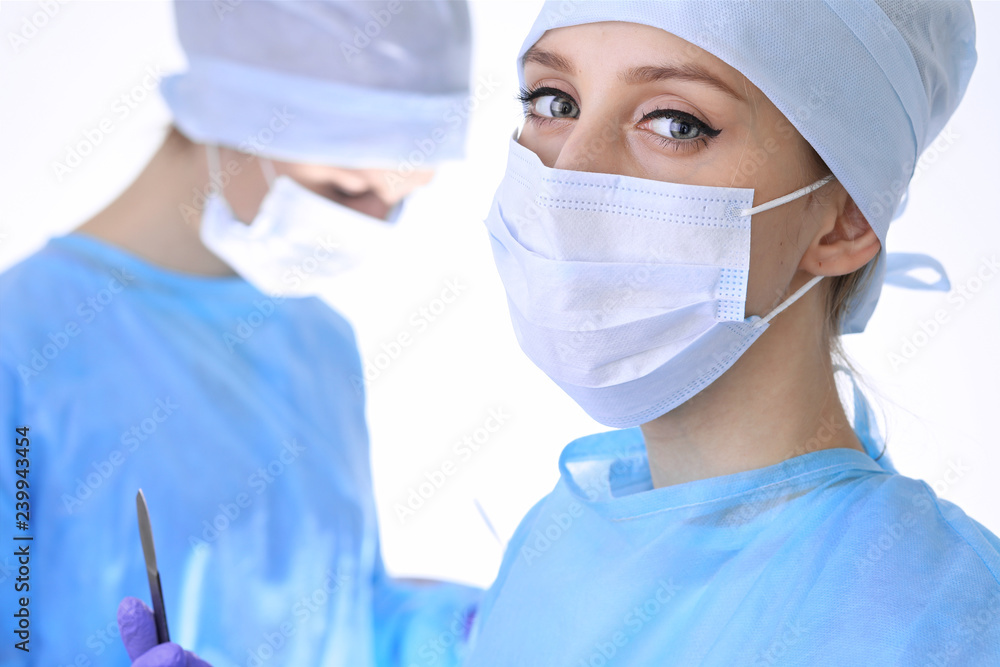 Surgeon doctor in mask performing operation. Focus on female intern girl. Medicine, emergency help concepts Surgeon doctor in mask performing operation. Focus on female intern girl. Medicine, emergency help concepts