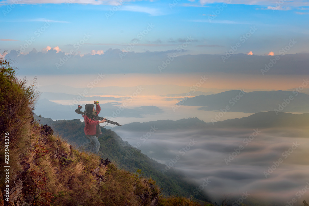 Fototapeta premium scenery view of the peak top of mountain with flowing of mist and fog under neath, photographer treking hiking the forest along mountain