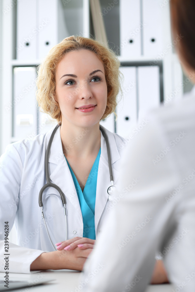 Happy blonde female doctor and patient discussing medical examination results. Medicine, healthcare and help concept Happy blonde female doctor and patient discussing medical examination results. Medicine, healthcare and help concept