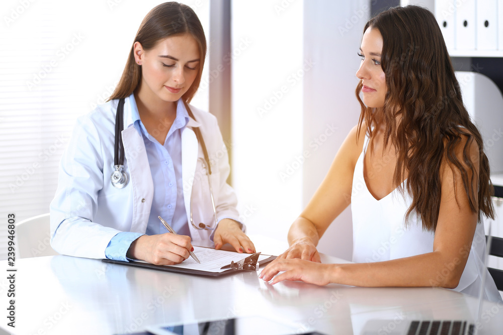 Doctor and happy patient talking while sitting at the desk. The physician or therapist discussing healthy lifestyle. Health care, medicine and patient service concept Doctor and happy patient talking while sitting at the desk. The physician or therapist discussing healthy lifestyle. Health care, medicine and patient service concept