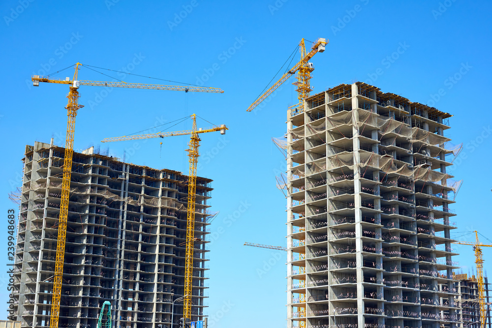 Building cranes and building under construction against sky.