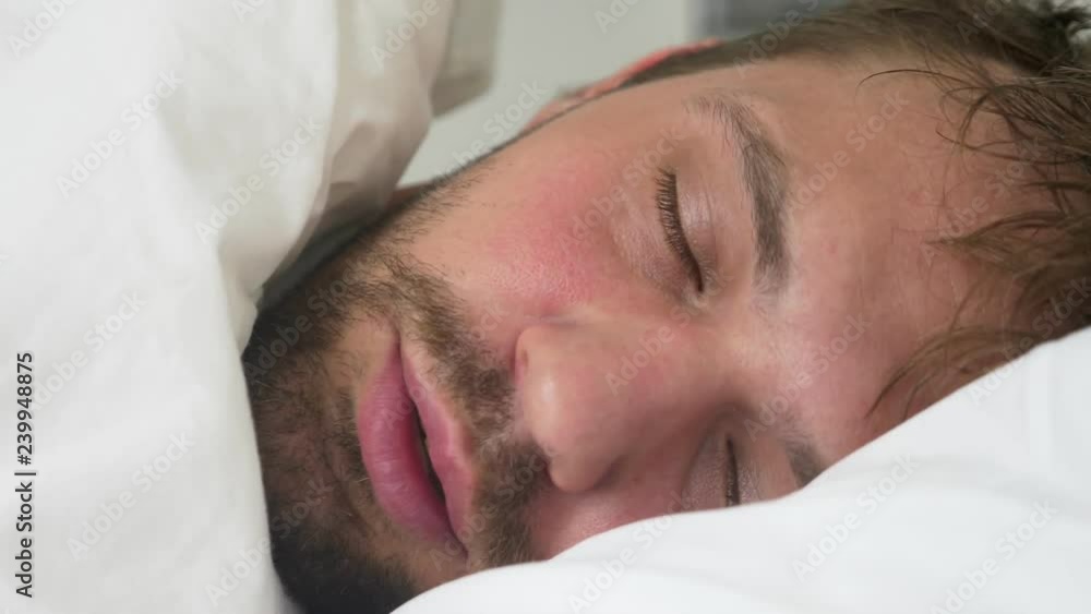 sick young man with fever asleep in bed, covered by a blanket sick young man with fever asleep in bed, covered by a blanket